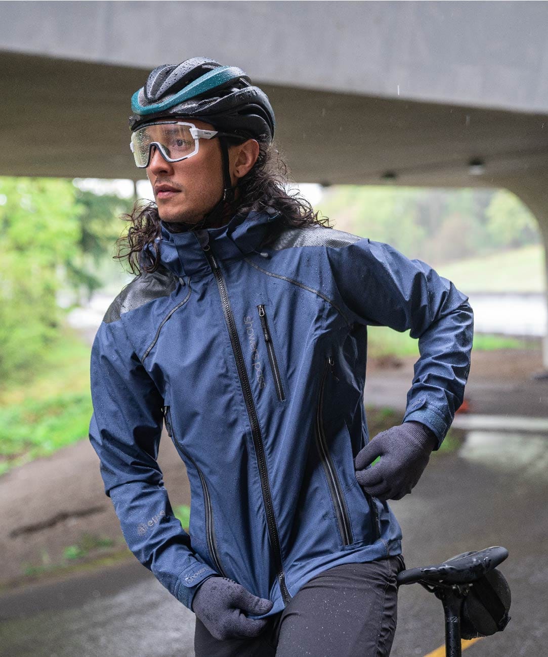 A cyclist at a stop wearing a blue rain jacket in the rain