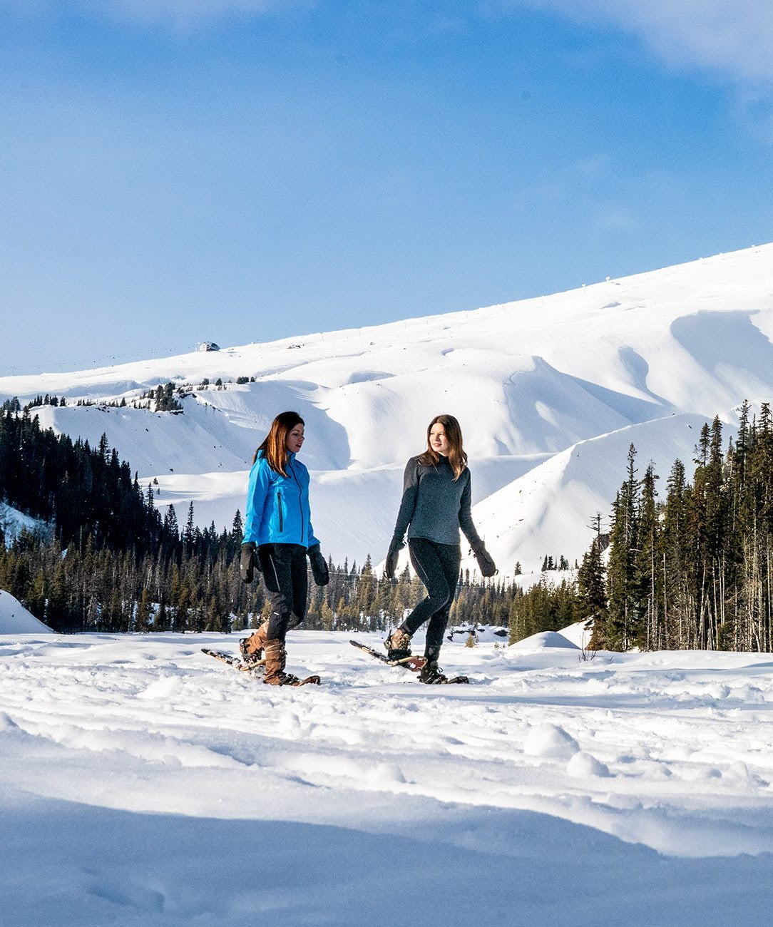 Two friends in snowshoes trekking through a snowy terrain wearing Showers Pass waterproof clothing